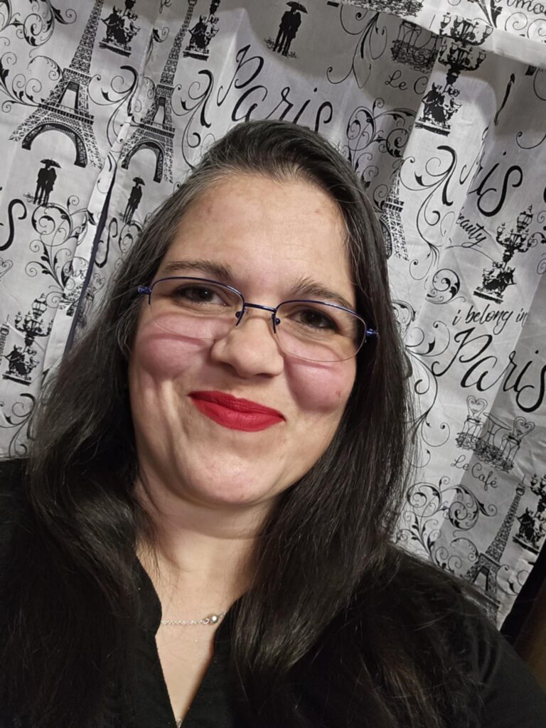 MJ Sumrall smiling in a black top and glasses.